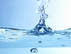 A drop of water plunges into a body of water, creating a ripple effect